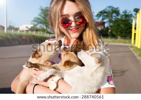 Young woman play with small puppies at the park,hugs and playing,stray dogs looking for a home , the dogs in the shelter , homeless little puppies.beautiful little puppies , a girl kisses and hugs