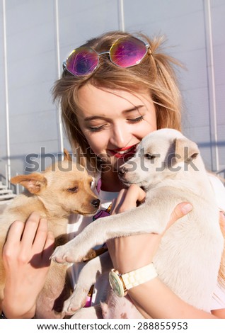 Young woman play with small puppies at the park,hugs and playing,stray dogs looking for a home,the dogs in the shelter,homeless little puppies.beautiful little puppies  a girl kisses and hugs