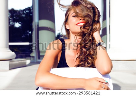 Fashion lifestyle portrait of young happy pretty woman laughing and having fun on the street at nice sunny summer day, listening favorite music at earphones,stylish vintage outfit,bright fresh colors.
