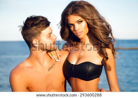 Vacation photo of happy young teen couple.Happy sunny summer outdoor portrait of young stylish couple while kissing on the beach tropical island. Wearing luxury fashion outfits, evening sunlight.