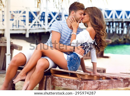 Romantic young couple together outdoors on summer day.Caucasian couple enjoying the beach view.Enjoy time together,lovely couple on the beach,kissing lops,party on beach,tan couple,fashionable outfit