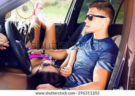 Portrait of young man with his beautiful girlfriend on a road trip. Couple driving in nature in a open car.Young couple kissing in the car. Couple in love on road trip having fun. bright sunlight.