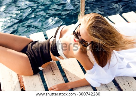 Young sexy woman laying near pool at hot day, wearing sunglasses and looking down,fashionable outdoor summer collection.strapless bikini swimwear neoprene front zipper,Brazilian,floral bikini,triangl