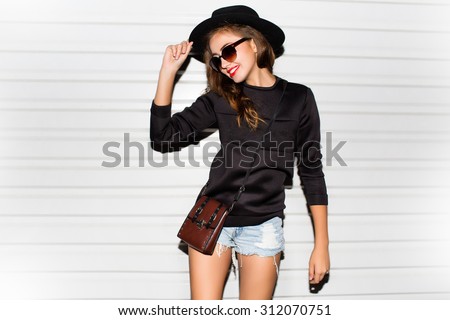 Young girl doing emotion.Dressed in a black shirt, black sweater,black hat,glasses and bright lips,trendy clothes.wearing vintage sunglasses,outfit and hat,vacation style,bright colors.Sensual woman
