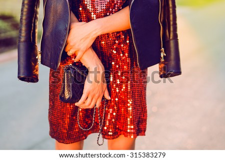 Close-up fashion portrait of young stylish hipster girl posing at sunset,stylish woman\'s look,leather jacket,party handbag,toned colors,soft vintage colors,red dress,cocktail dress,fashion object