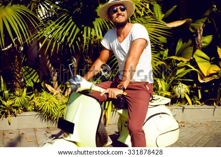 Full length portrait of a handsome young man enjoy his days,ride vintage vespa on the city,Casual man posing outdoor on the street,palms background.Street style,mans fashion.hand watch,mans hat,pastel