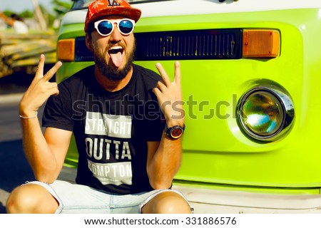vintage image of hipster man hiker,casual hipster outfit,cap and big sunglasses,bearded man outdoors,toned,retro style,peace sign,hippie man,surfer man having fun,reflecting sunglasses,retro bus