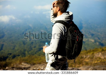 Outdoor portrait of hiker man posing on the mountain,freedom concept.tourist looking at dramatic river.Man hiker looking at landmarks in forest nature.Ascent to the volcano,travel guide,equipment