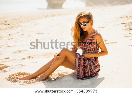 Outdoor street fashion style woman,posing with trendy sunglasses,and boho style dress,amazing beach style girl,windy hair,toned,sugaring legs,beach wear,tender skin,