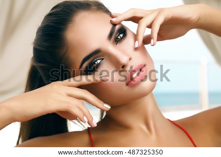 Winking sensual model Girl touching her face,manicure nails,beauty teen face isolated on white background.Joyful young fashion woman with bright make up,red lips and nails,make-up artist,model face