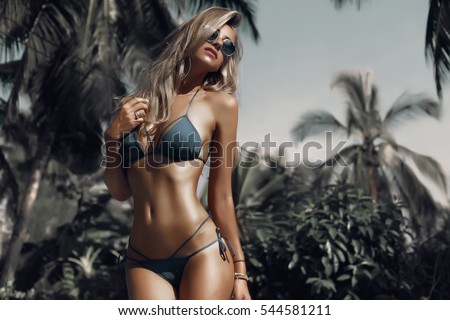 Hight fashion colors,Glamour Portrait of pretty beautiful fashion woman in green bikini posing in summer near the sea and blue sky in sunshine with gorgeous sunglasses,tropic  island girl on vacation