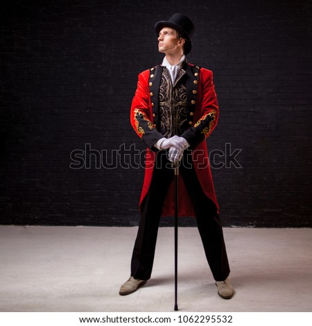 Showman. Young male entertainer, presenter or actor on stage. The guy in the red camisole and the cylinder. Bright tailcoat, suit