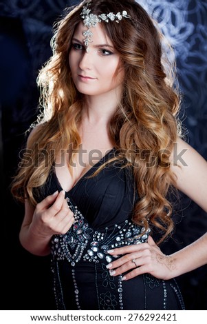 beautiful girl  with long brown curled hair, dark background, vertical cropping
