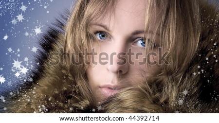The beautiful girl in a winter fur collar and magic snowflakes