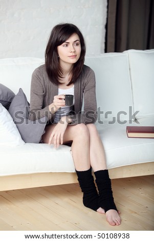 young beautiful girl in the apartment drinks morning coffee