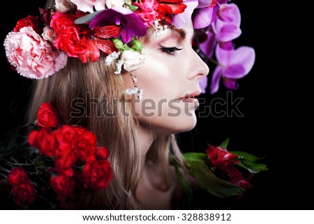 young beautiful woman in wreath of flowers, black background. Profile