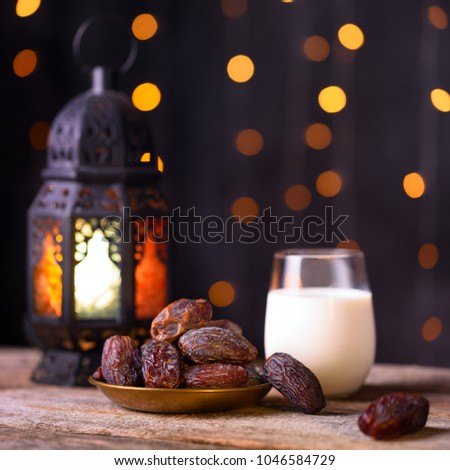 Ramadan concept. Dates close-up in the foreground. Ramadan Lantern and glass of milk on a wooden table. Circle lights in blurred background. Space for text on the right. Square 1:1 frame.