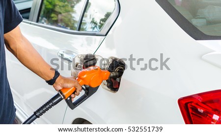 Closeup hand pumping Fuel nozzle gasoline fuel in white car at gas station