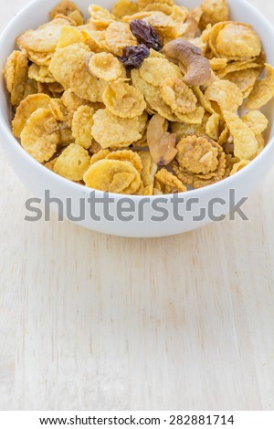 Mix corn flake cereal in a white bowl on the table.