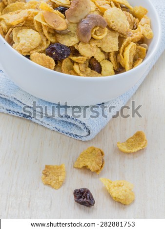 Mix corn flake cereal in a white bowl on the table.