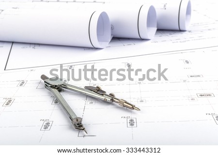 Compasses placed on the desk, filled with building plans. In order to work in a building