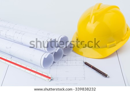 Yellow safety helmet, pencil, scale ruler on plan drawing background