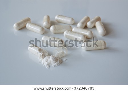 Probiotics. White medicine capsules probiotic powder inside, one capsule open.