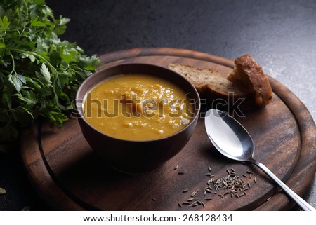 Pumpkin, carrot and lentil soup and bread on the black table