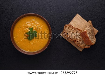 Pumpkin and lentil soup and bread. Black background. Top view