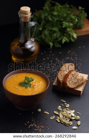 Carrot and pumpkin soup, bread and olive oil on the black table