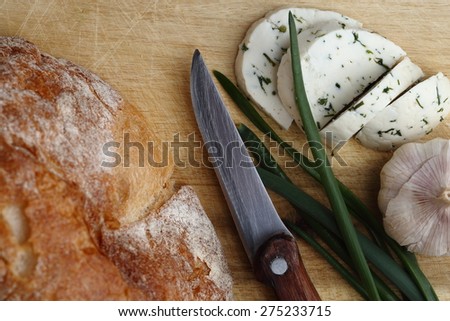 Cheese slices, green onion, garlic and bread on the wooden table