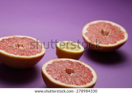 Lemon and grapefruits on bright lilac background