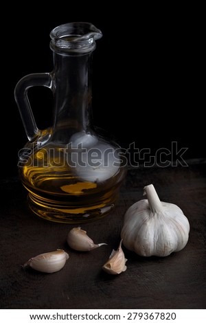 Bottle of olive oil and garlic on the black table. Black background
