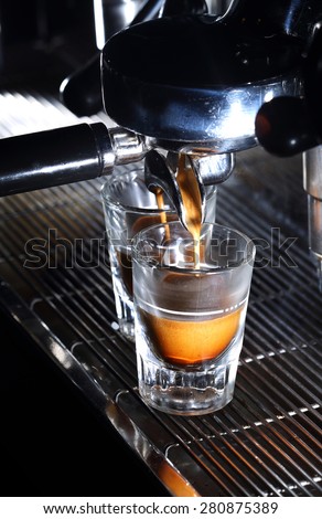 Espresso machine brewing a coffee. Coffee pouring into shot glasses. Toned image