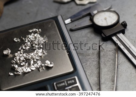 Tools of jewellery. Jewelry workplace on metal background. Weigh-scales with granules of silver.