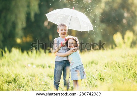 Happy children in the rain, shallow depth of field,  Funny kids playing outdoors in spring park. Brother and sister playing in the rain in summer, focus on children or raindrops