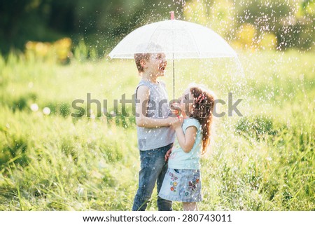 happy kids playing outdoor in raining spring park. shallow depth of field,focus on children or raindrops