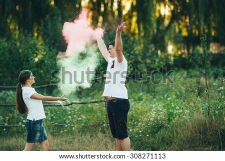 beautiful young couple playing with colorful paints outdoors. Couple throwing each other colorful paint. Man and woman spend fun time outdoors