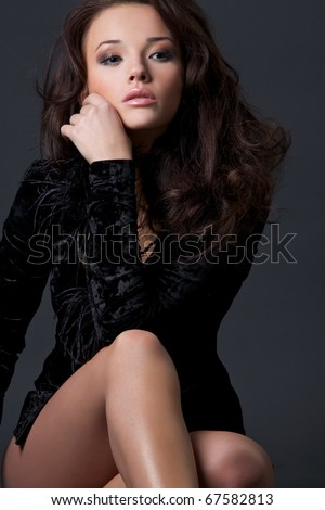 Portrait of the beautiful girl in a black velvet dress with wavy hair.
