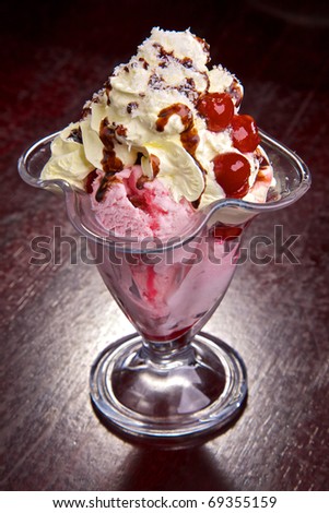 Fruit with ice-cream and cream with chocolate topping. A cherry in cream