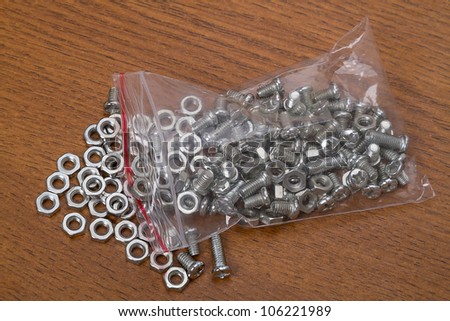 Plastic bag with small nuts and bolts on the brown table