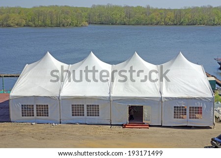 A large tent on the sandy banks of the river