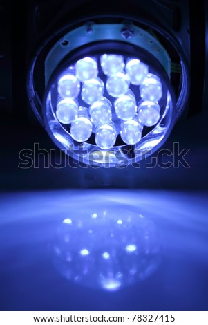 Light-emitting diode flashlight turned on against a blue background.