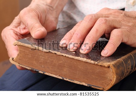 The ancient book in hands at the blind old woman