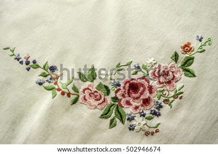 Embroidery satin stitch pink roses with other flowers and leaves on cotton cloth