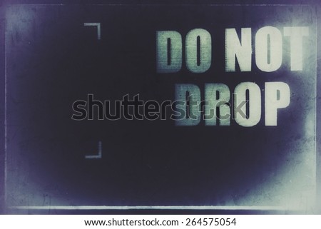 Do not drop, white text print and markings on a blue background, from a cardboard box with a distressed and inverted overlay.