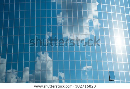 Blue sky and clouds reflected in windows of modern office building