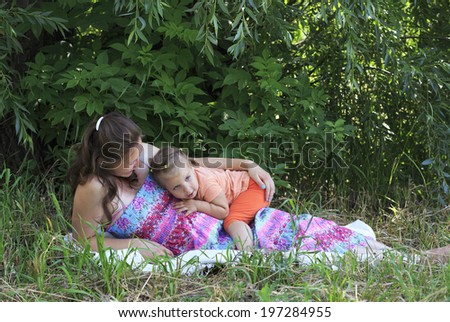 Beautiful pregnant woman tenderly deals with a little daughter.
