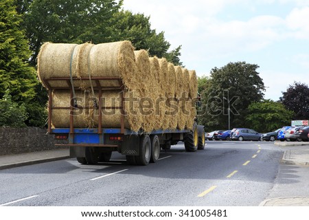 Kilkenny, Ireland - August 23, 2014: Tractor transporting straw bales in irish countryside