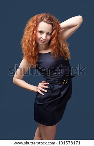 Redhead young girl in dark blue dress posing in studio